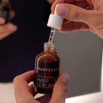 hand-oeffnet-harvekst-hair-serum-und-zieht-pipette-aus-braunglasflasche-heraus